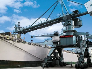 Ein Schiffsbe- und Entlader steht an einem Schiff für den Transport von Zement und ist in Betrieb.