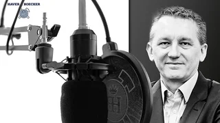 Portrait of Klaus Sklorz next to a studio microphone with pop filter, black and white, for the podcast meshTALK by Haver & Boecker Drahtweber.