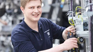 Ein Auszubildender arbeitet an einer Maschine.
