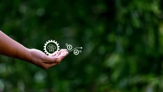 A hand holding a digital CO₂ capture symbol against a green natural background symbolizes sustainable technology and environmental awareness.