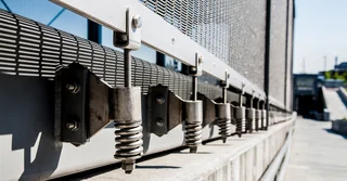 Bottom attachment of architectural mesh facade cladding