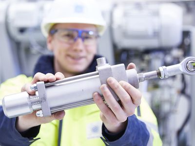 HAVER & BOECKER technician holding an upgraded component used to modernize packing equipment for improved performance and efficiency