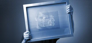 A man looks through a coated screen printing stencil.