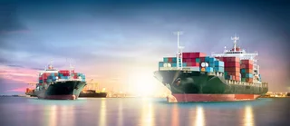 Two container-laden cargo ships at sunrise in the port, a symbol of ballast water treatment and global trade.