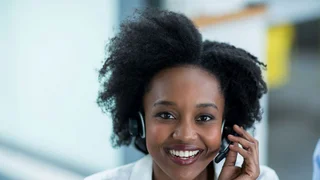 Eine Frau mit Headset nimmt einen Hotline-Anruf entgegen.