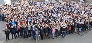 Ein Gruppenbild unserer Mitarbeiterinnen und Mitarbeiter winkend auf dem Hof.