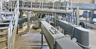 Ein installiertes Fördersystem mit Durchflusskontrolle für Baustoffe in einem Werk.