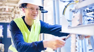 Mitarbeiter prüft Maschine - Vermeiden Sie unerwartete Stillstände mit einer regelmäßigen präventiven Wartung